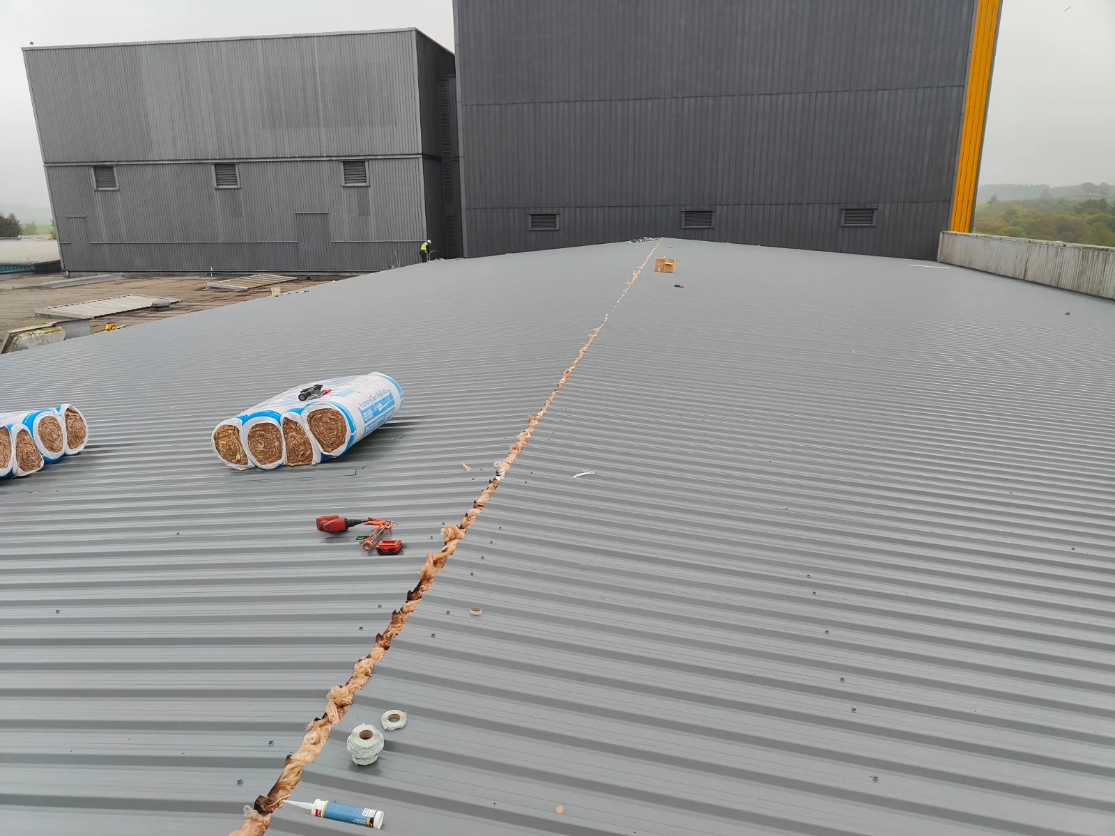 Insulation rolls and tools laid out on a new industrial roof sheet installation